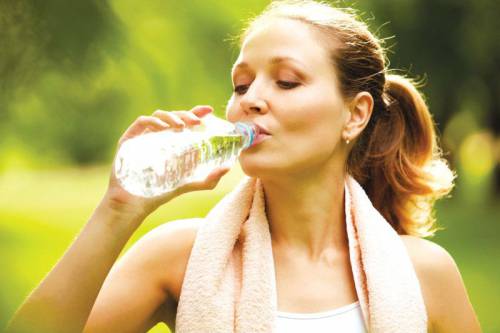 Девушка пьет воду после тренировки